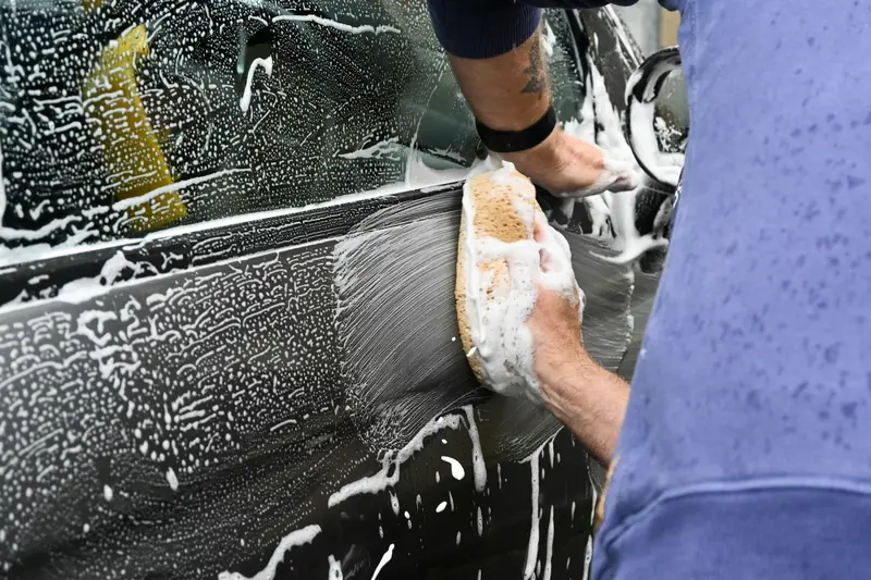 Hand washing a car with a foam-covered wash mitt